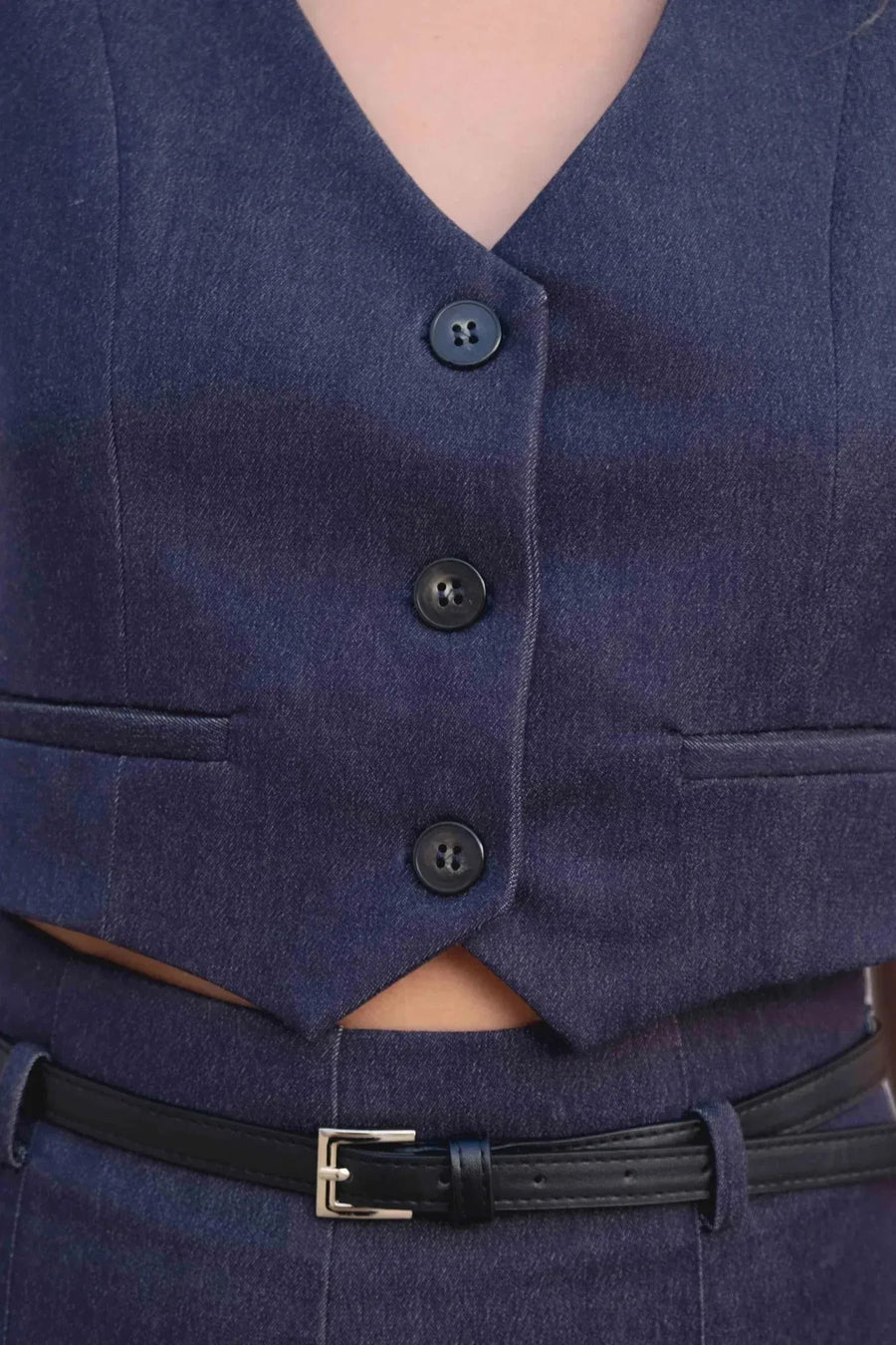 Gros plan sur le gilet court sans manche femme en bleu indigo, mettant en avant les boutons et le col V féminin.