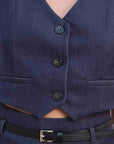Gros plan sur le gilet court sans manche femme en bleu indigo, mettant en avant les boutons et le col V féminin.
