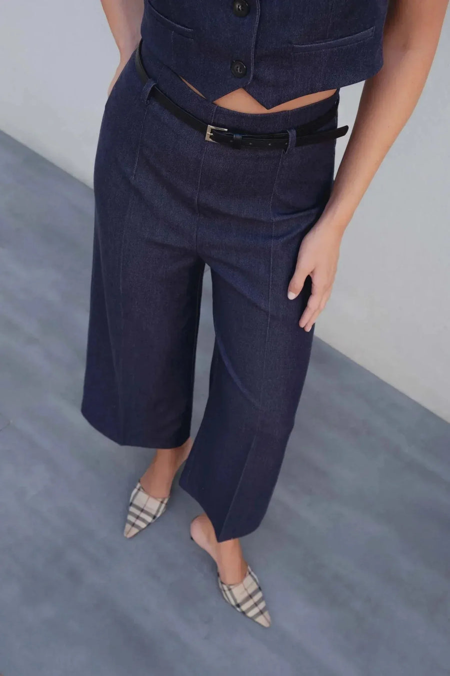 Détail du gilet court sans manche femme en bleu indigo chic, avec un pantalon ajusté et ceinture noire, parfait pour un look moderne.