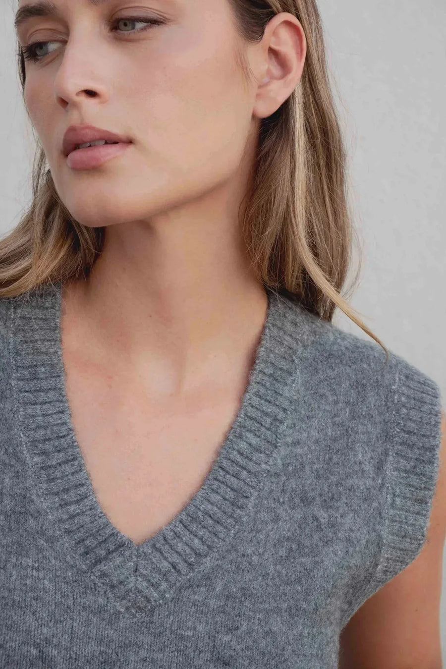 Gros plan sur un gilet tricoté femme col V gris, montrant la texture douce et moderne. Ce gilet tricot sans manche femme est idéal pour superposer.
