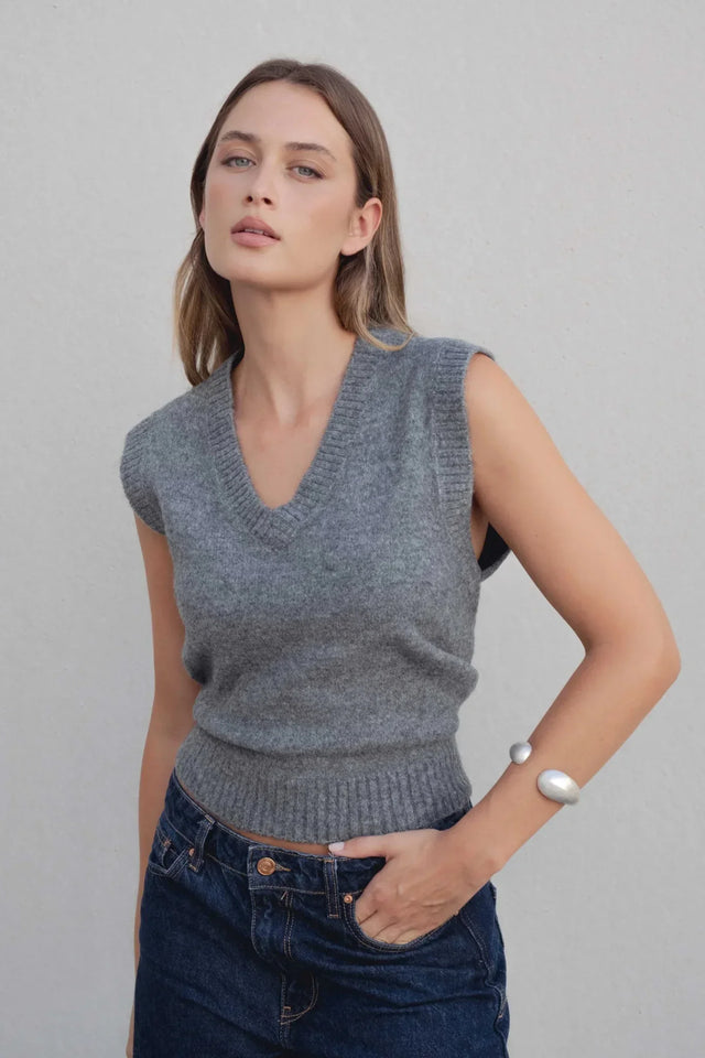 Gilet tricoté femme col V gris porté par un modèle, mettant en valeur son style élégant. Ce gilet tricot sans manche femme est parfait pour un look décontracté et chic.