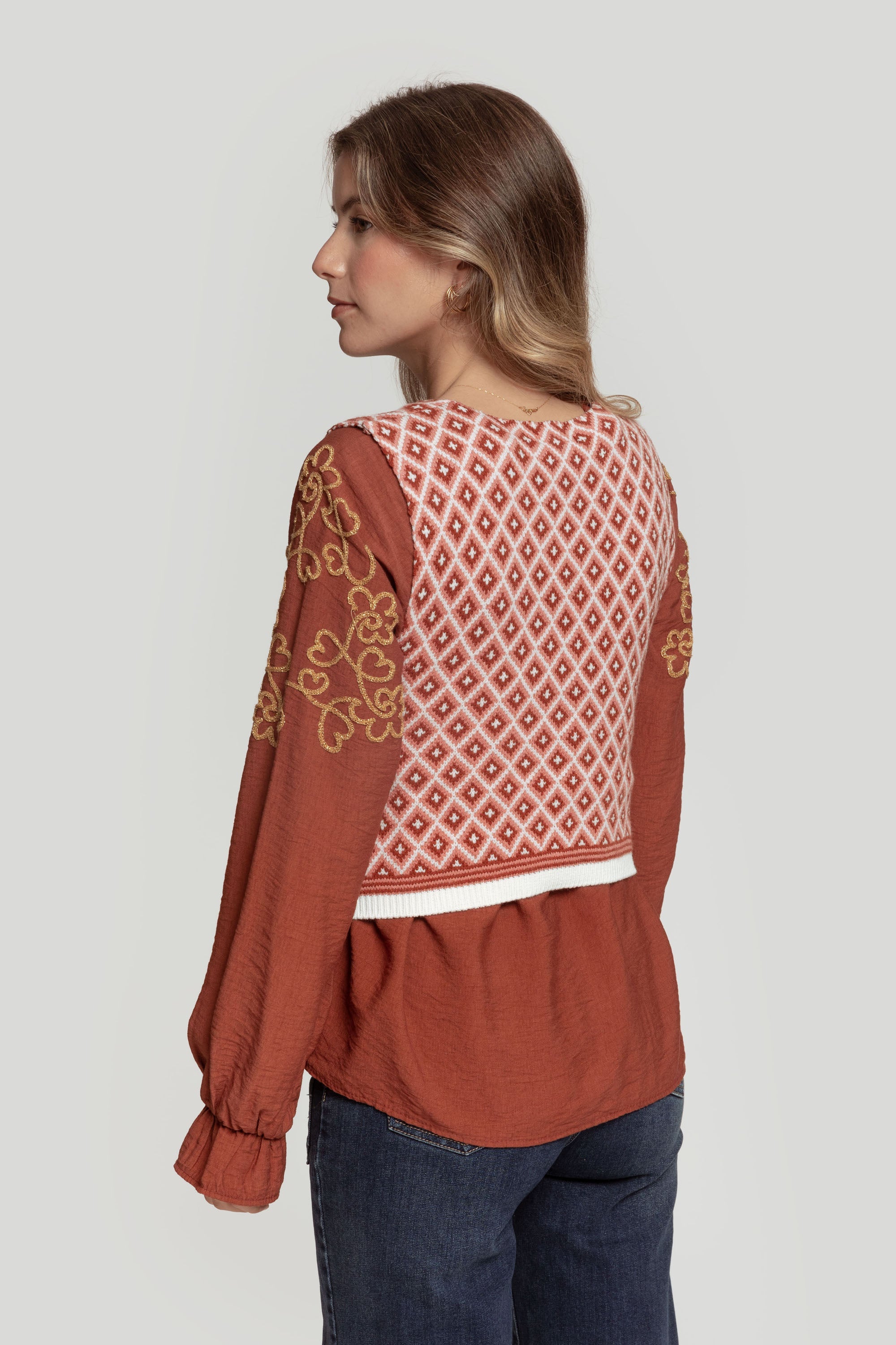 Vue de dos d&#39;une femme portant un gilet femme en maille sans manches géométrique sur une blouse rouge, créant un look tendance.
