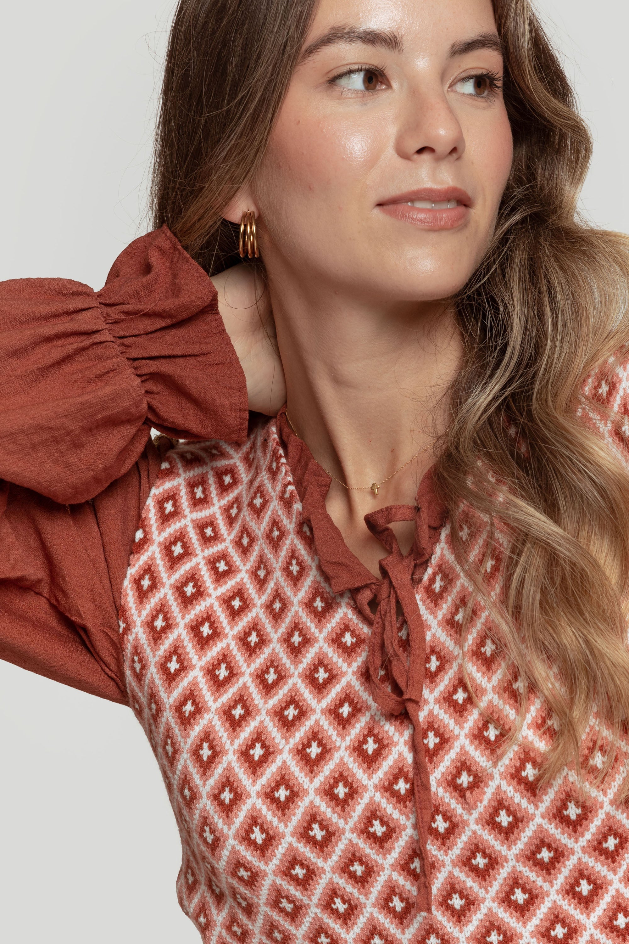 Portrait d&#39;une femme dans un gilet femme en maille sans manches géométrique, mettant en avant son sourire et son style.