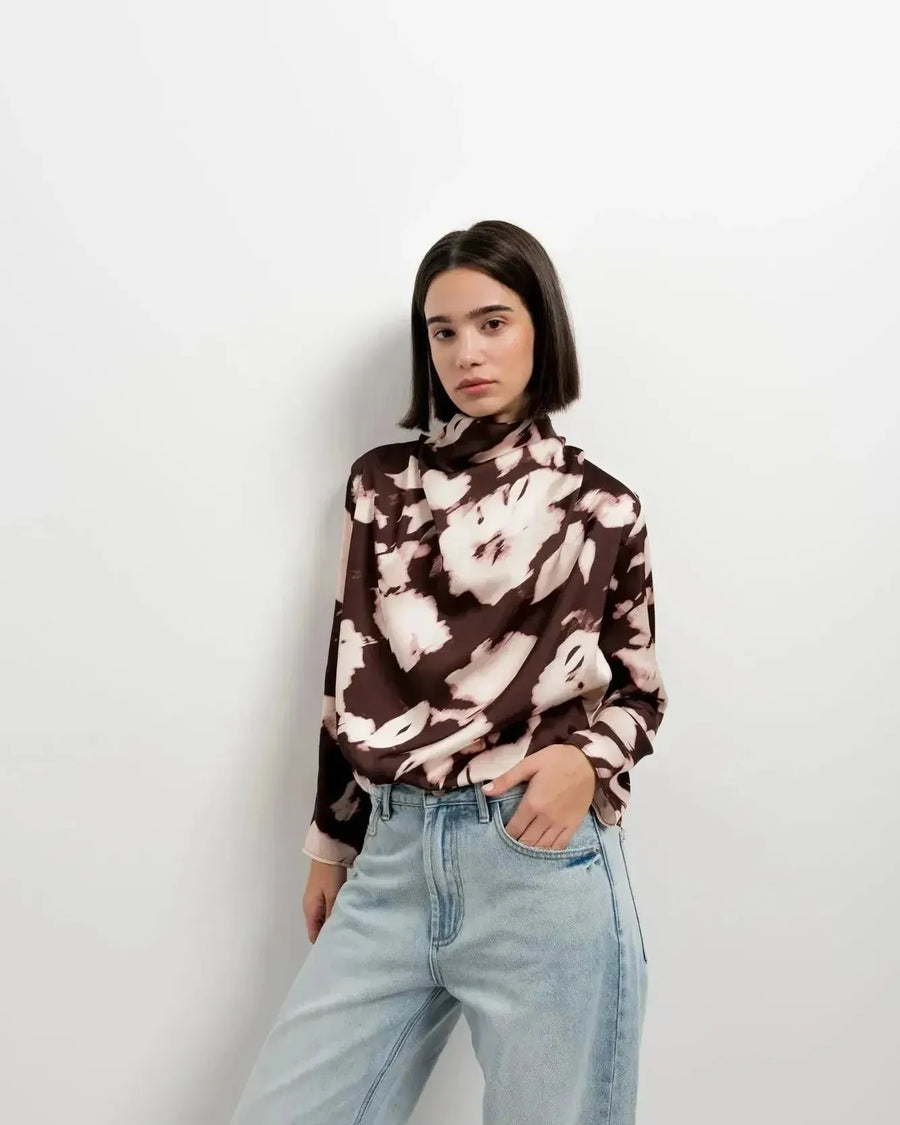 Modèle posant dans un studio avec la blouse femme à col bénitier et imprimé abstrait, combinée avec un jean, pour un look actuel.