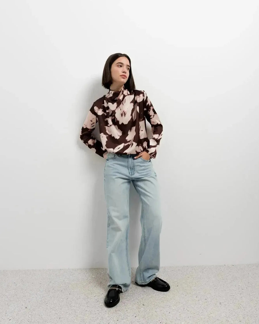 Portrait du modèle avec la blouse femme à col bénitier et imprimé abstrait, capturant l'élégance et le confort de la tenue.