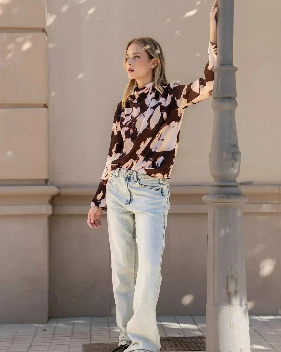 Modèle posant élégamment avec la blouse femme à col bénitier et imprimé abstrait, associée à un jean décontracté.