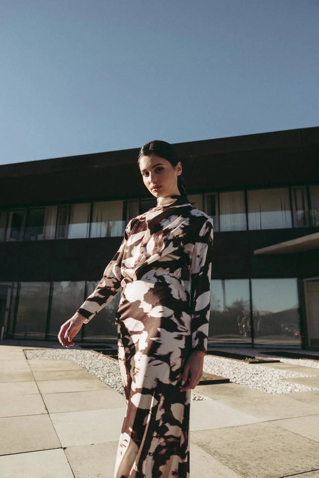 Modèle en extérieur portant la blouse femme à col bénitier et imprimé abstrait, ajoutant une touche de style à un look chic.