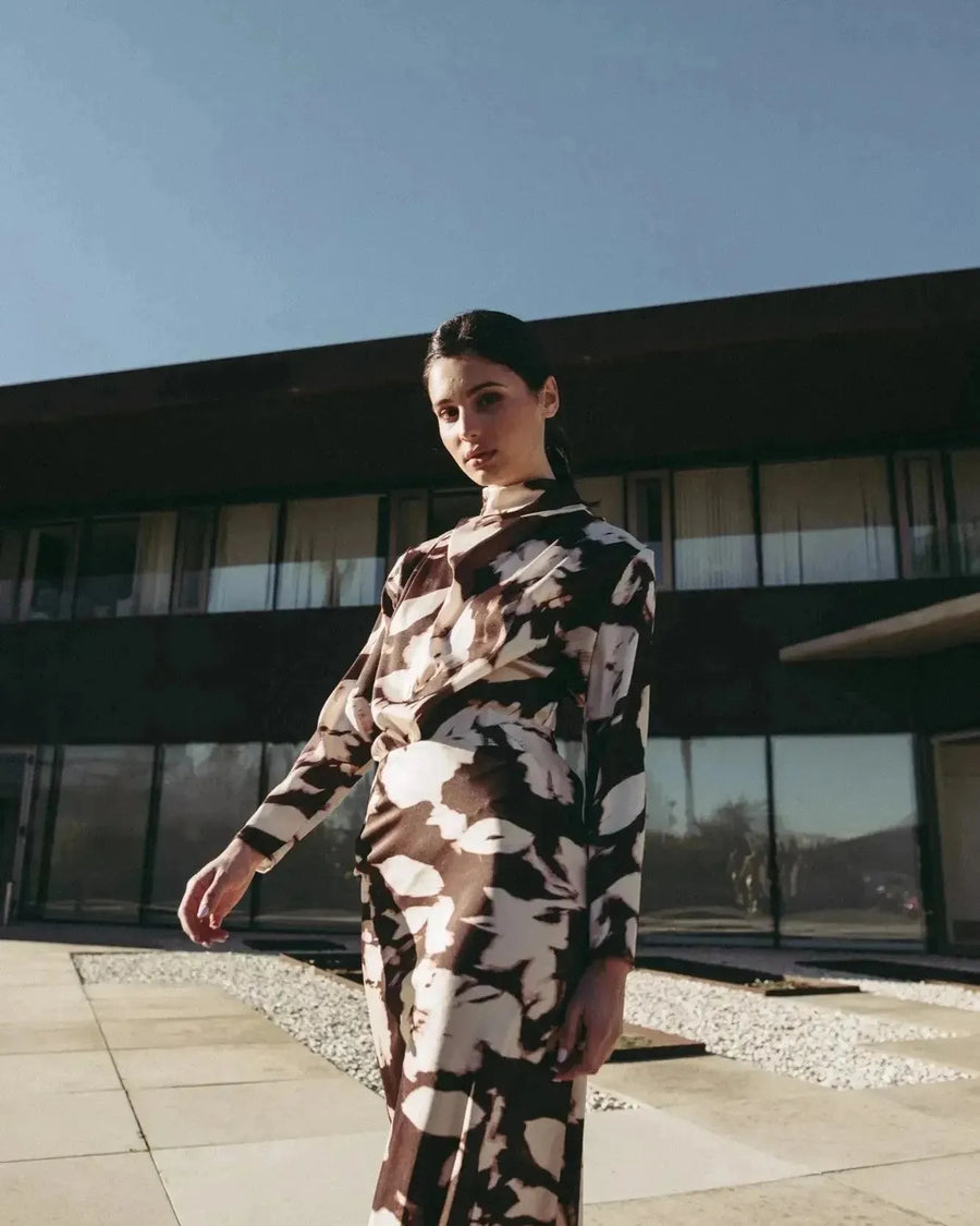 Modèle en extérieur portant la blouse femme à col bénitier et imprimé abstrait, ajoutant une touche de style à un look chic.