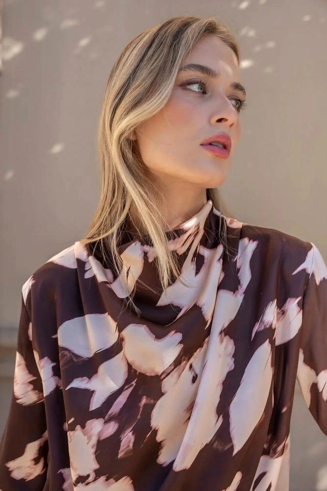 Gros plan sur le modèle avec la blouse femme à col bénitier et imprimé abstrait, montrant le design élégant et moderne.