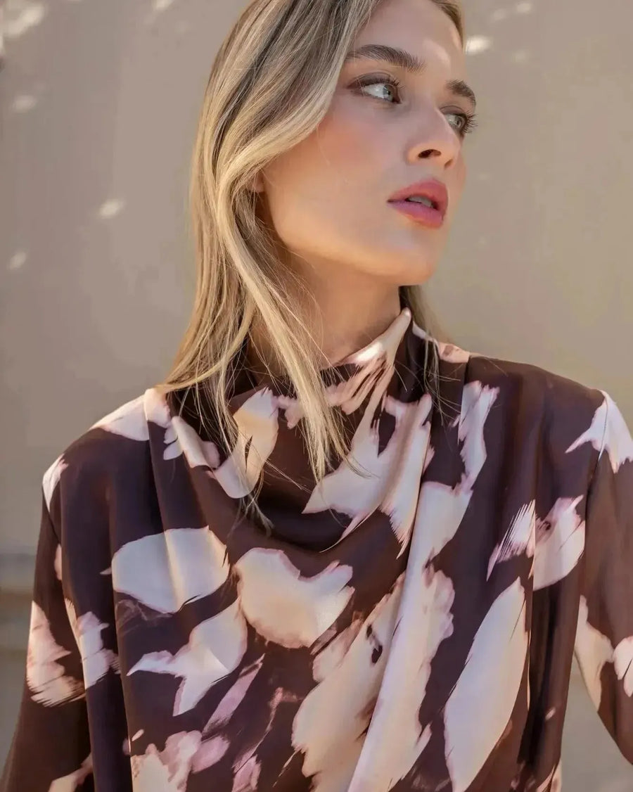 Gros plan sur le modèle avec la blouse femme à col bénitier et imprimé abstrait, montrant le design élégant et moderne.