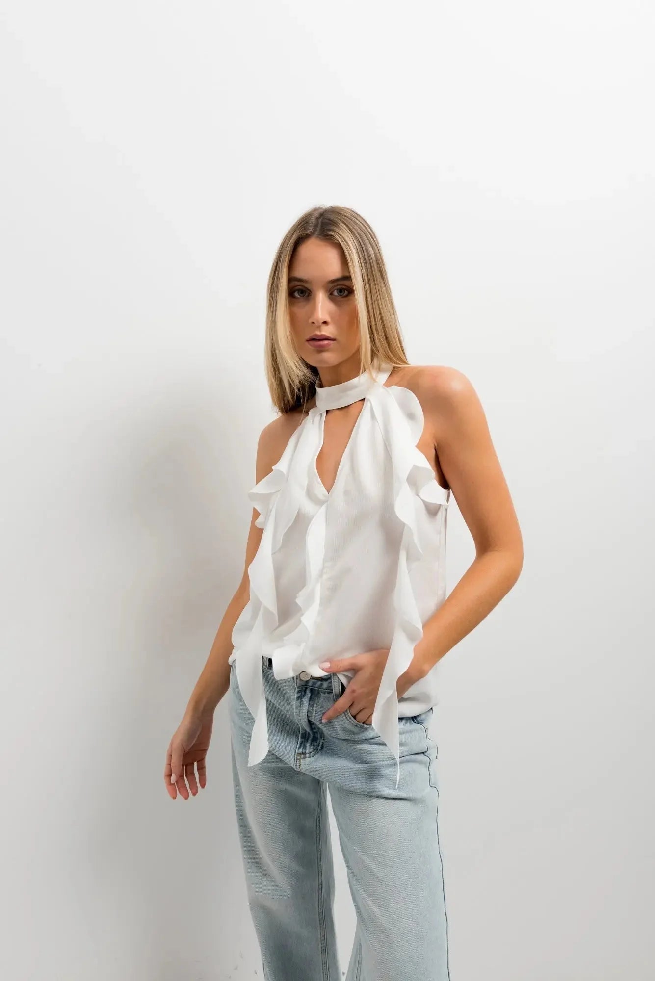 Haut à volants femme chic en tissu lisse, avec volants accentués, présenté dans une tenue stylée.