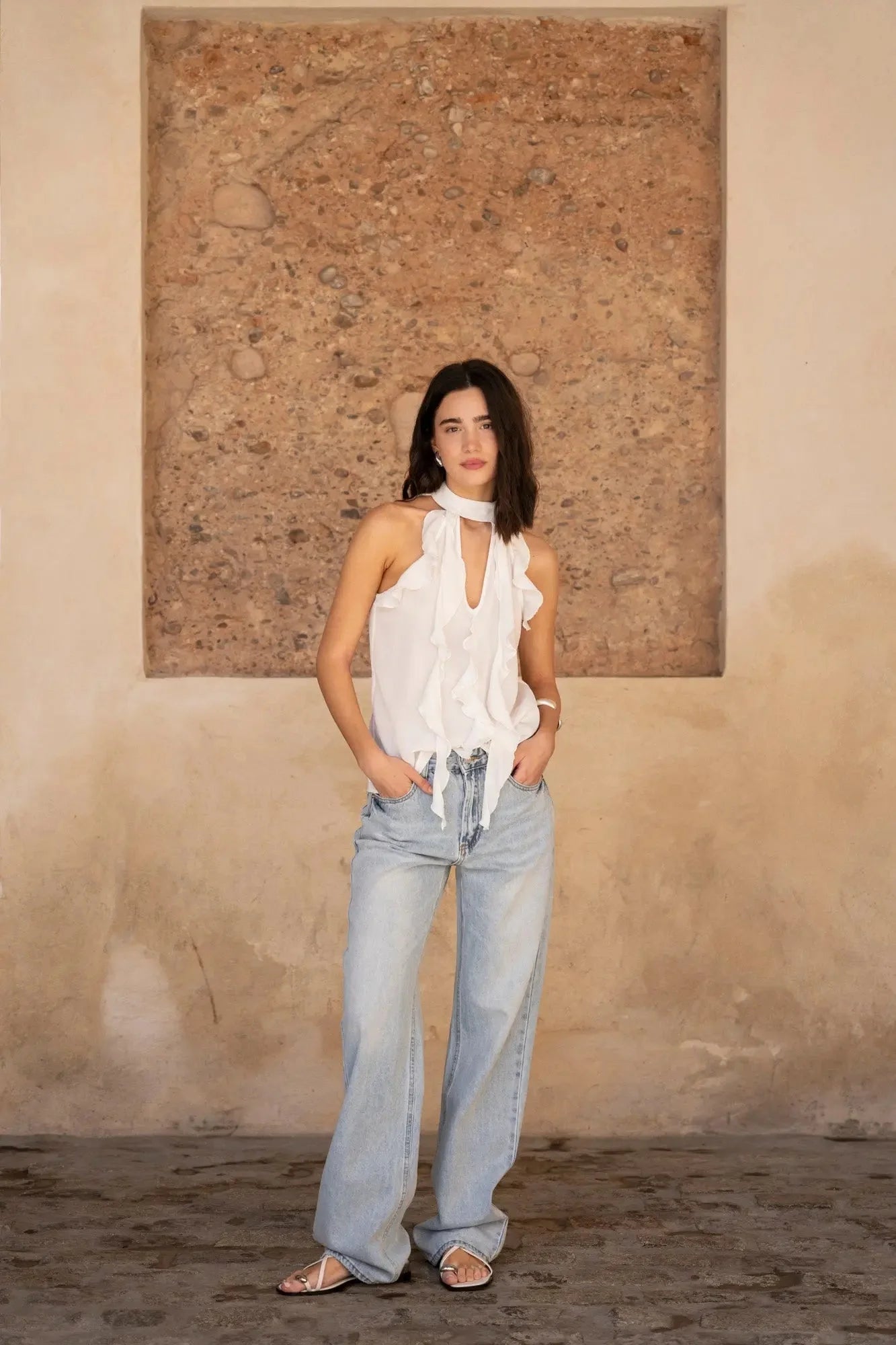 Haut à volants femme chic en tissu lisse, modèle élégant avec un look décontracté, accompagné d'un jean large.