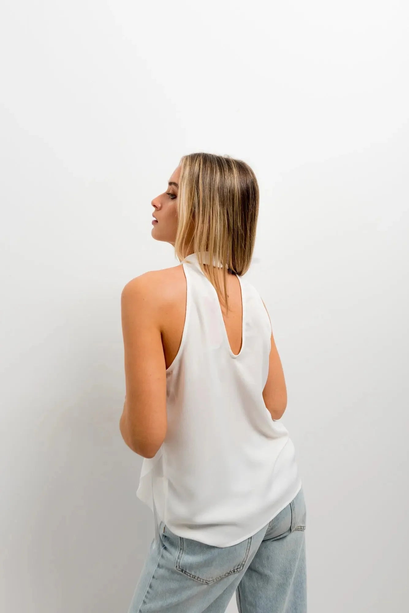 Vue arrière de haut à volants femme chic en tissu lisse, mettant en valeur le design moderne et élégant.