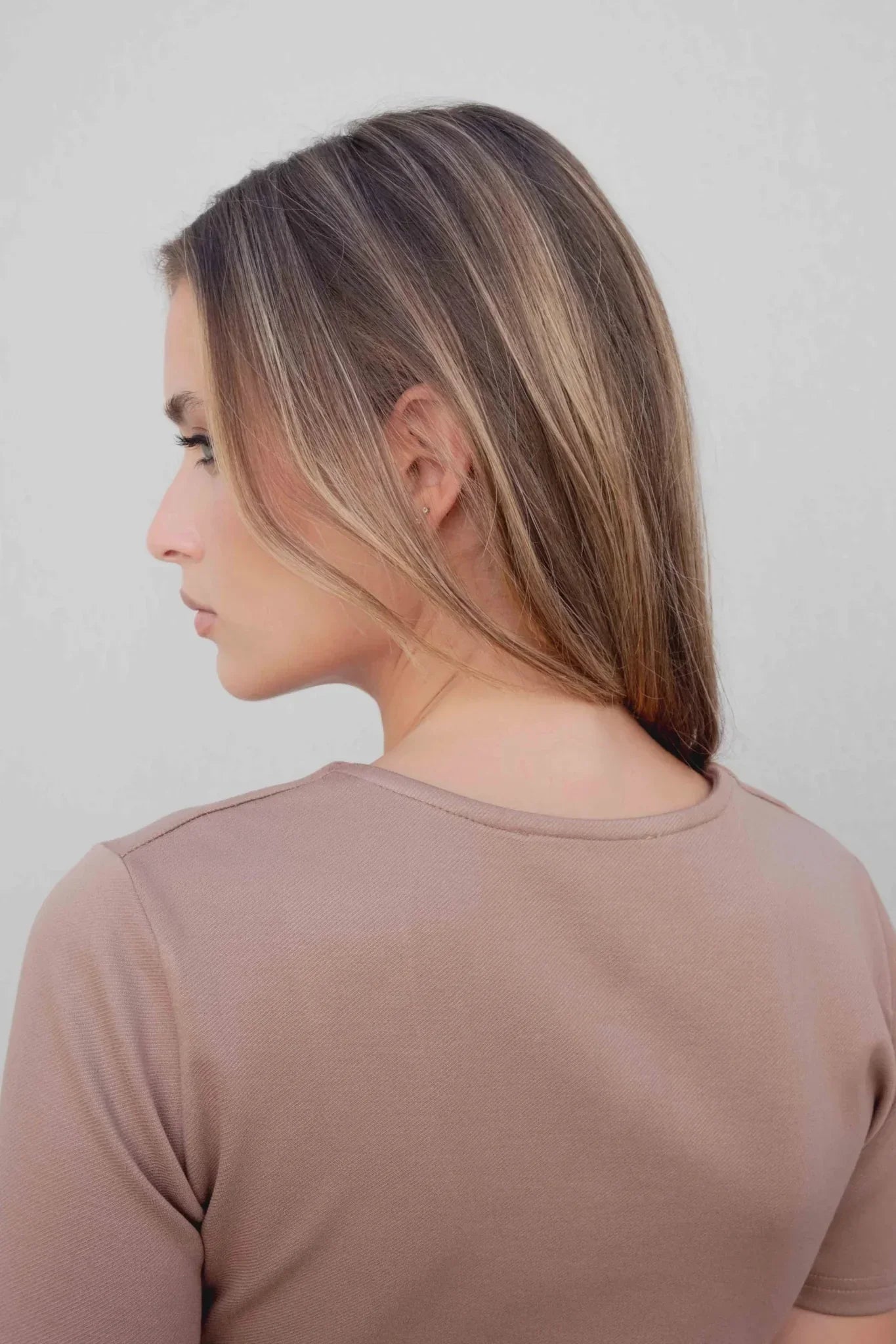 Femme avec longue chevelure brune highlights portant l’ensemble ajusté avec boucle effet écaille