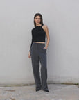 Haut asymétrique femme noir à une épaule, stylé avec un pantalon gris, parfait pour un look décontracté et tendance.