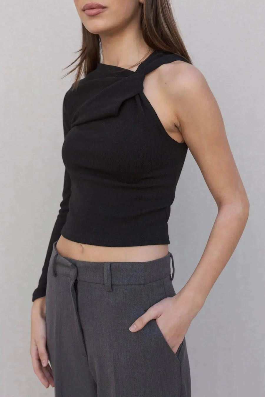 Détail du haut asymétrique femme noir à une épaule, soulignant le design audacieux et tendance.