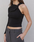 Détail du haut asymétrique femme noir à une épaule, soulignant le design audacieux et tendance.