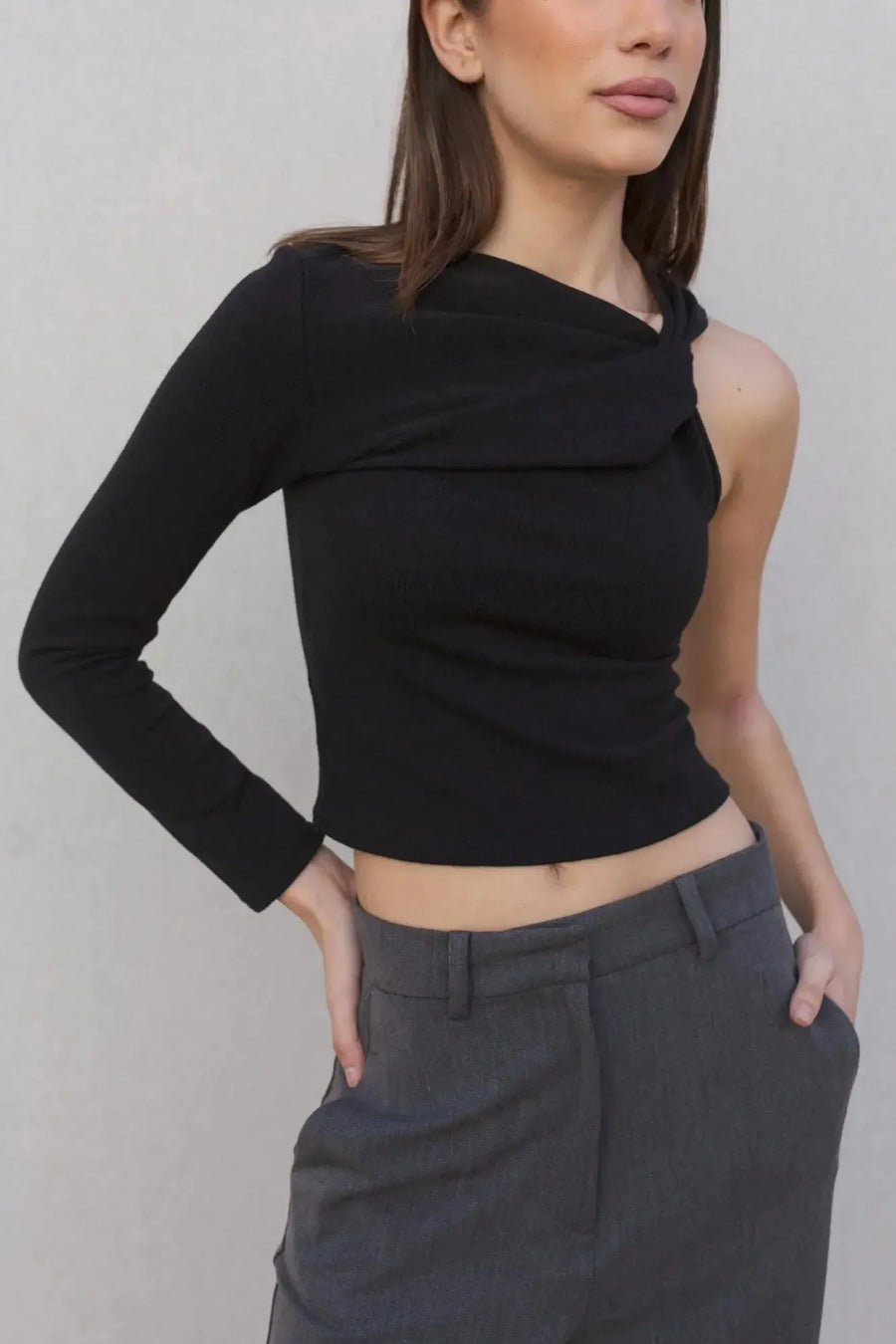 Haut asymétrique femme noir à une épaule, avec une pose qui met en avant le style contemporain et le confort.
