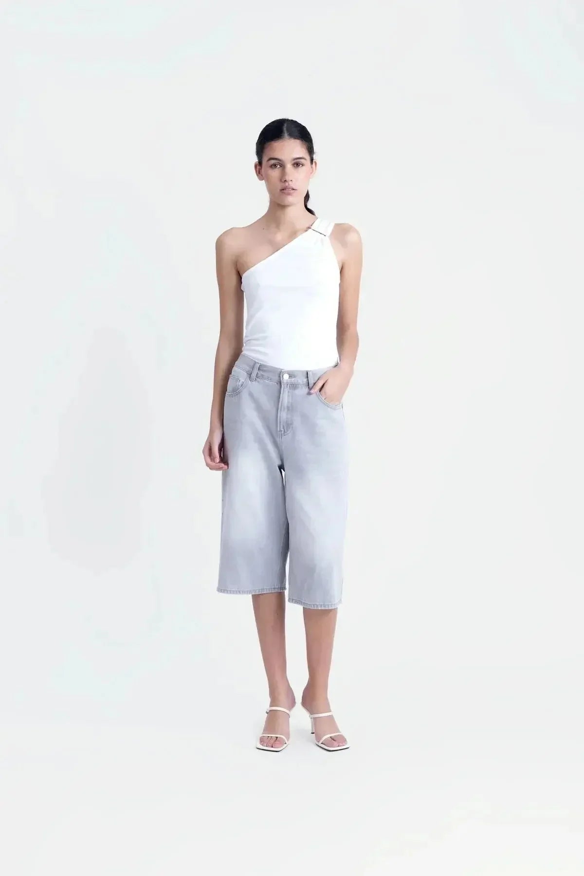 Modèle en plein pied portant un haut asymétrique blanc, associant élégance et confort pour toute occasion.