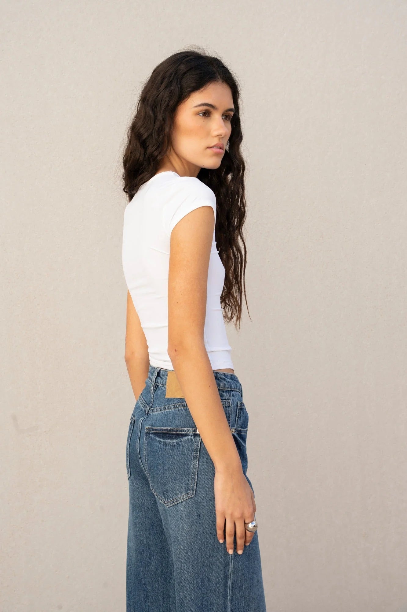 Femme portant un jean à jambe large avec ourlets retroussés et un top blanc côtelé