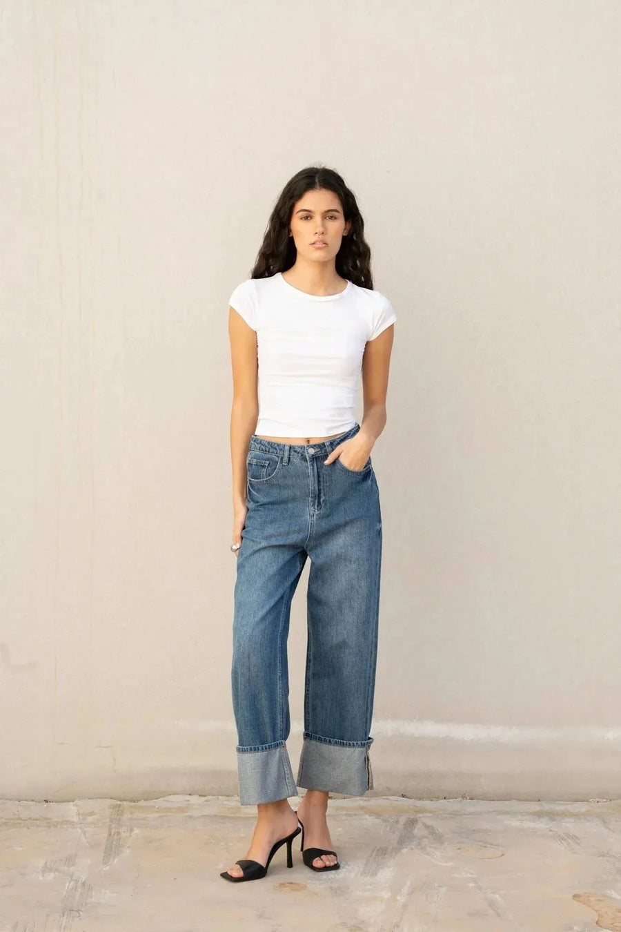 Une jeune femme porte un jean à jambe large et ourlets retroussés, mettant en avant le style casual du jean ample femme avec un tee-shirt blanc.