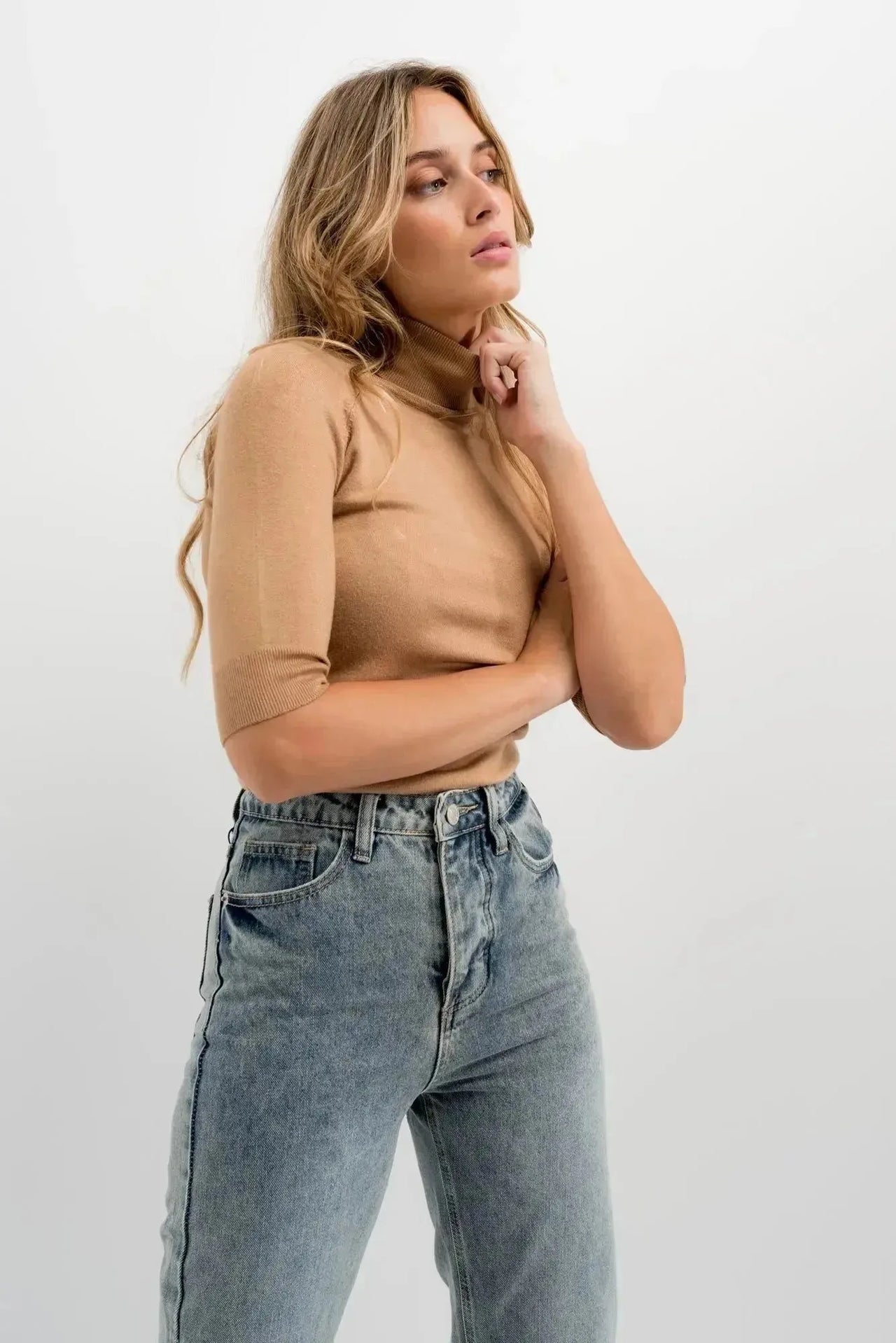 Femme avec un look de rue décontracté, portant un jean femme taille haute droit gris et un pull, en pleine réflexion.