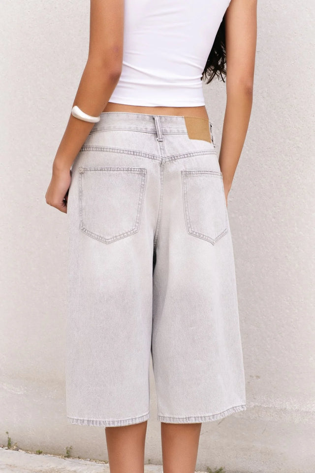 Arrière d'une femme posant en bermuda jean femme gris clair, mettant en valeur son style décontracté et contemporain.