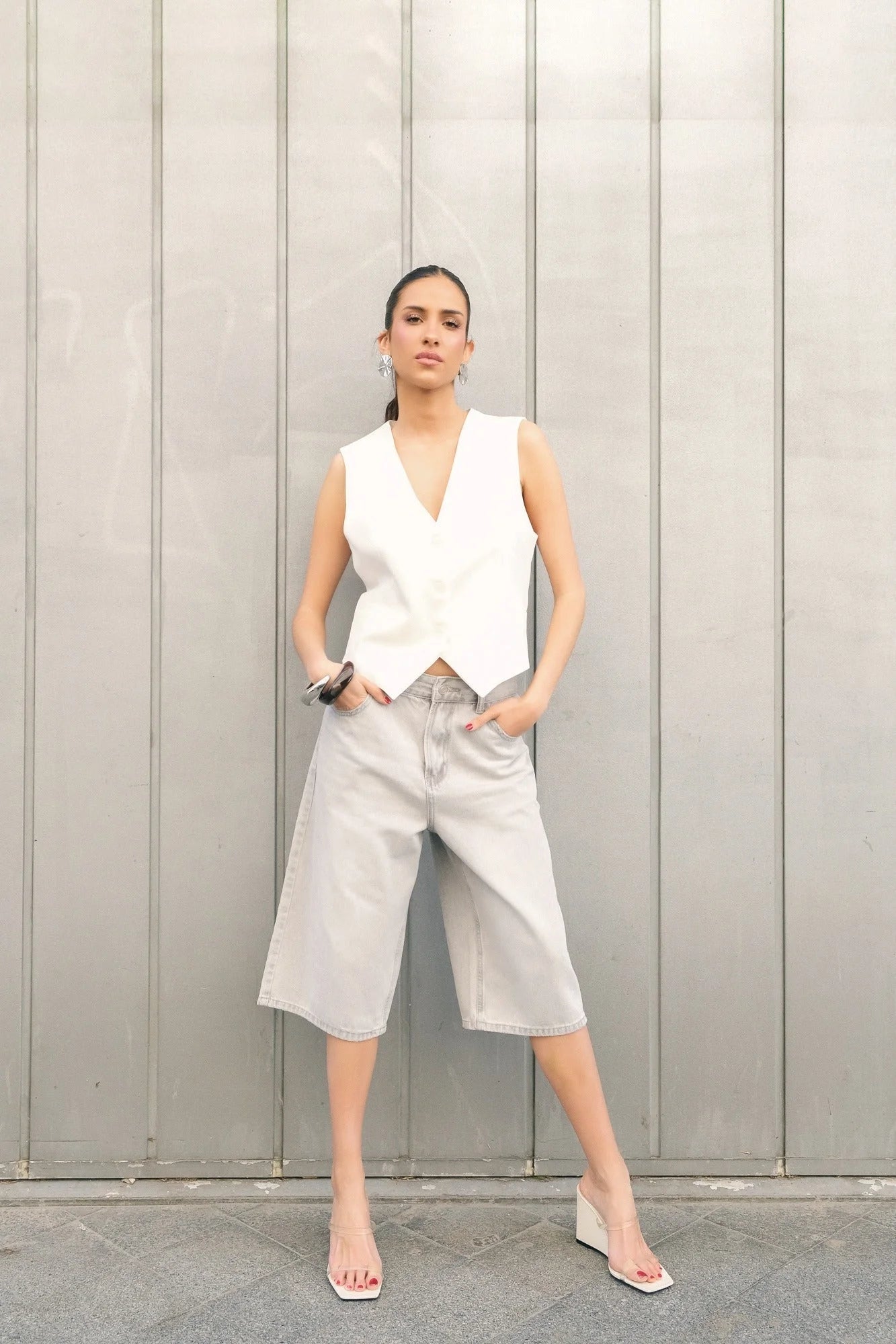 Femme portant un bermuda oversize en jean gris avec coupe large et débardeur blanc