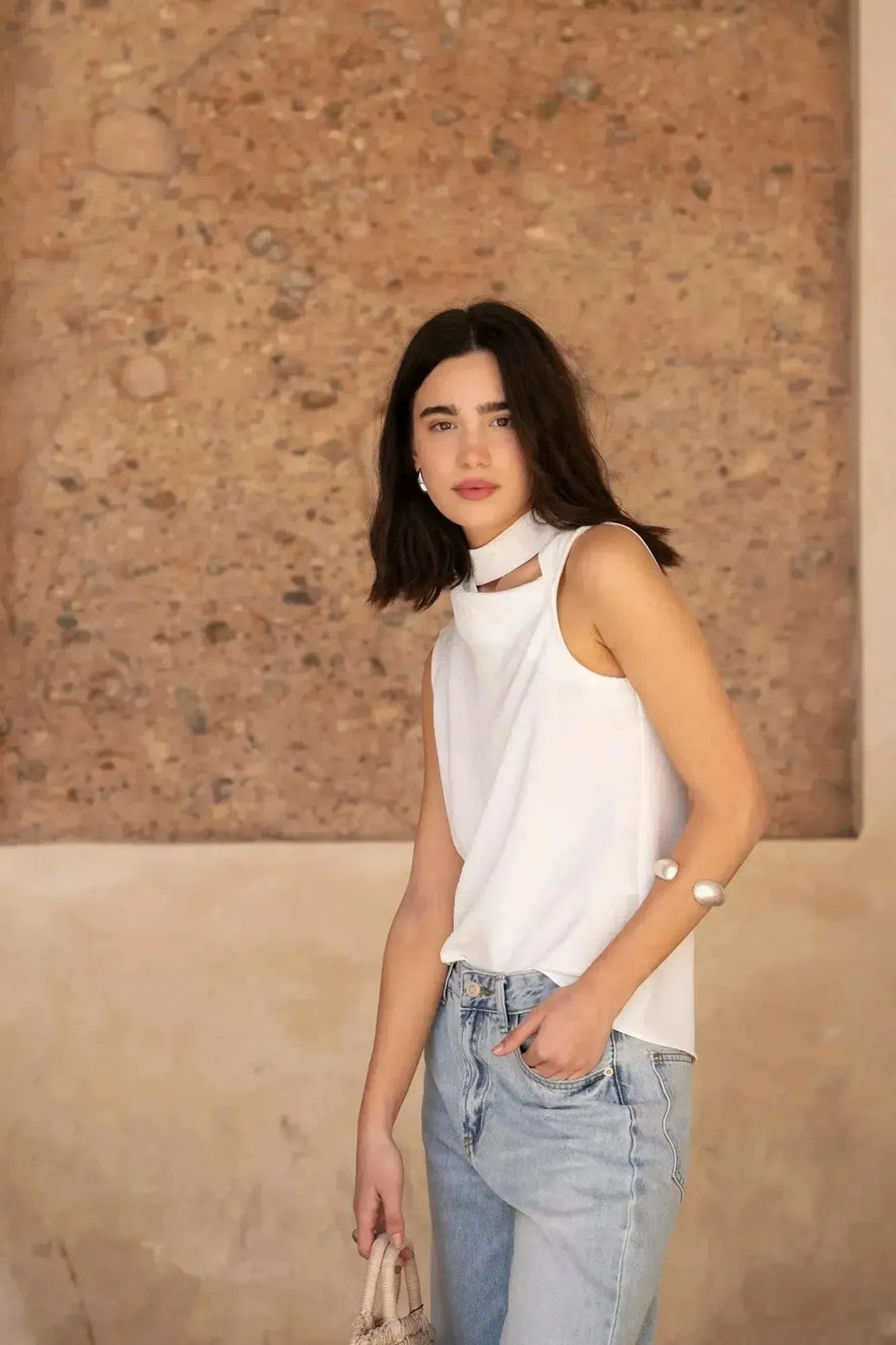 Femme regardant la caméra, habillée en blanc avec un Jean Jambe Large à la Coupe Flatteuse, parfaite illustration du style du jean jambe large femme.