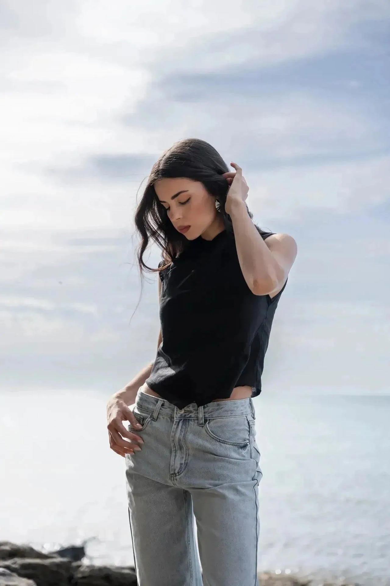 Modèle en noir posant sur la plage, portant un Jean Jambe Large à la Coupe Flatteuse, parfait pour un look décontracté avec le jean jambe large femme.