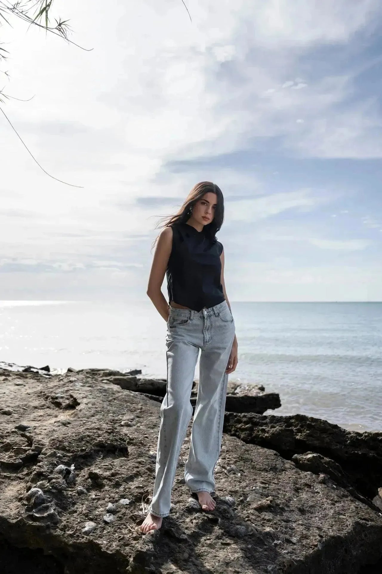 Modèle debout sur des rochers, arborant un Jean Jambe Large à la Coupe Flatteuse, offrant une silhouette flatteuse avec le jean jambe large femme.