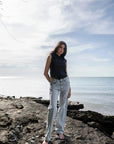 Modèle debout sur des rochers, arborant un Jean Jambe Large à la Coupe Flatteuse, offrant une silhouette flatteuse avec le jean jambe large femme.