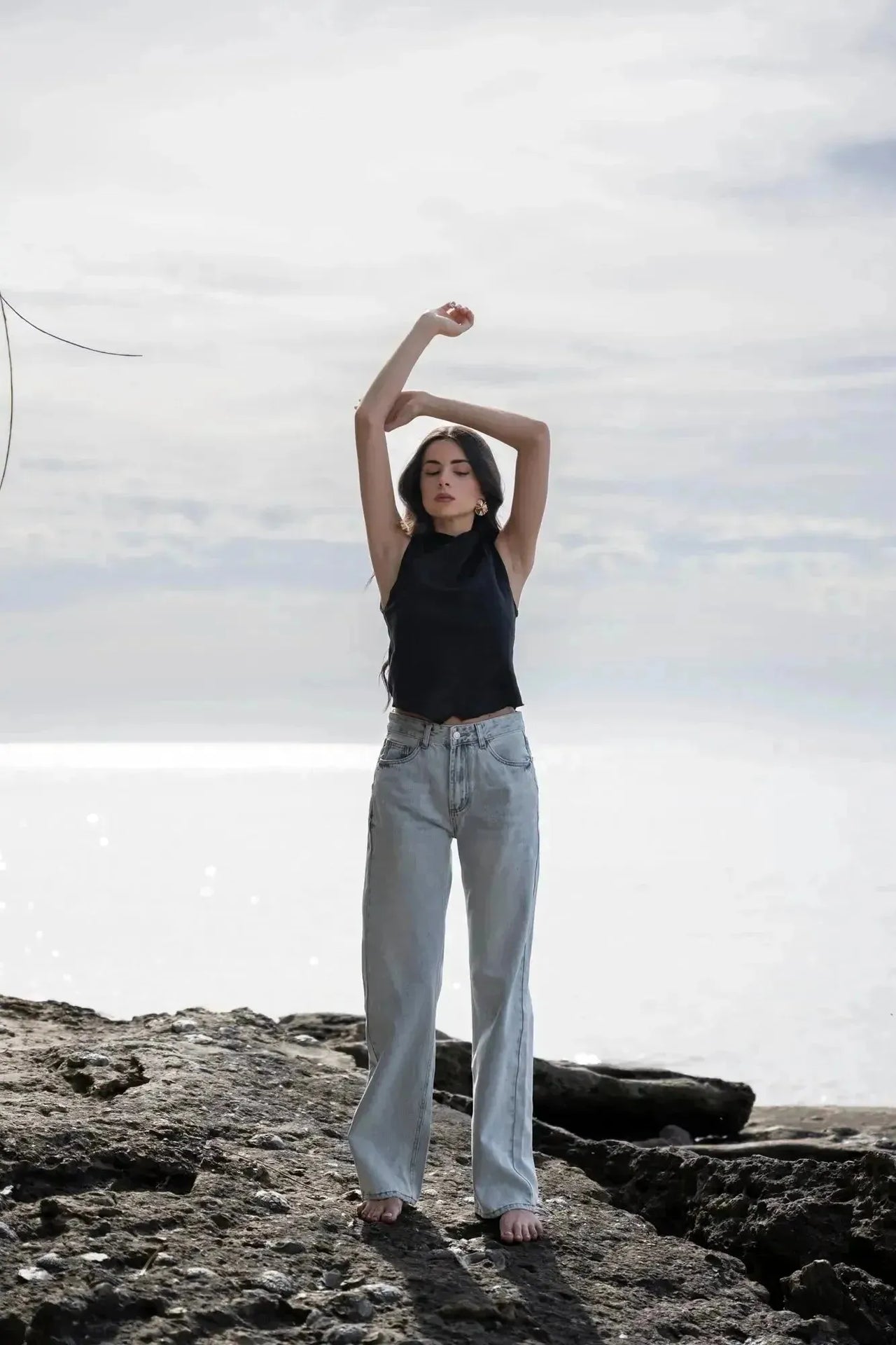 Femme levant les bras, vêtue d'un Jean Jambe Large à la Coupe Flatteuse, mettant en avant le confort et le style du jean jambe large femme.