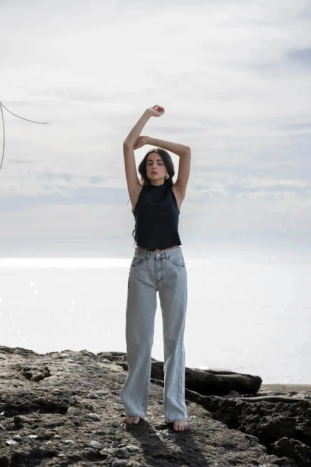 Femme levant les bras, vêtue d'un Jean Jambe Large à la Coupe Flatteuse, mettant en avant le confort et le style du jean jambe large femme.