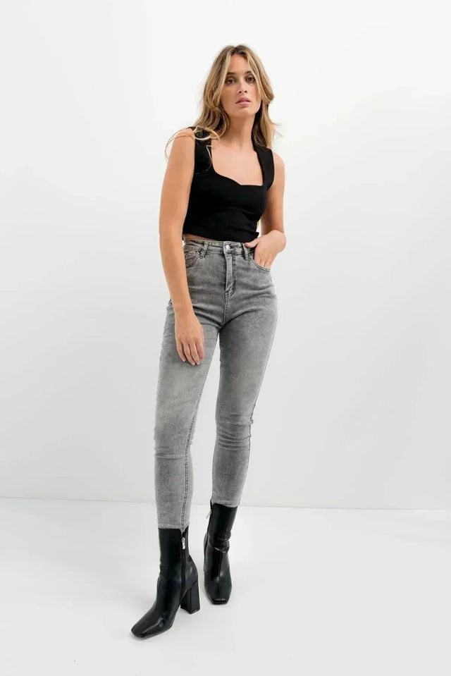 Jean Skinny Femme Taille Haute Sculptant Gris - Confort Optimal & Silhouette Sublimée, affiché par une femme en haut noir, mettant en valeur ses jambes avec des bottines noires.