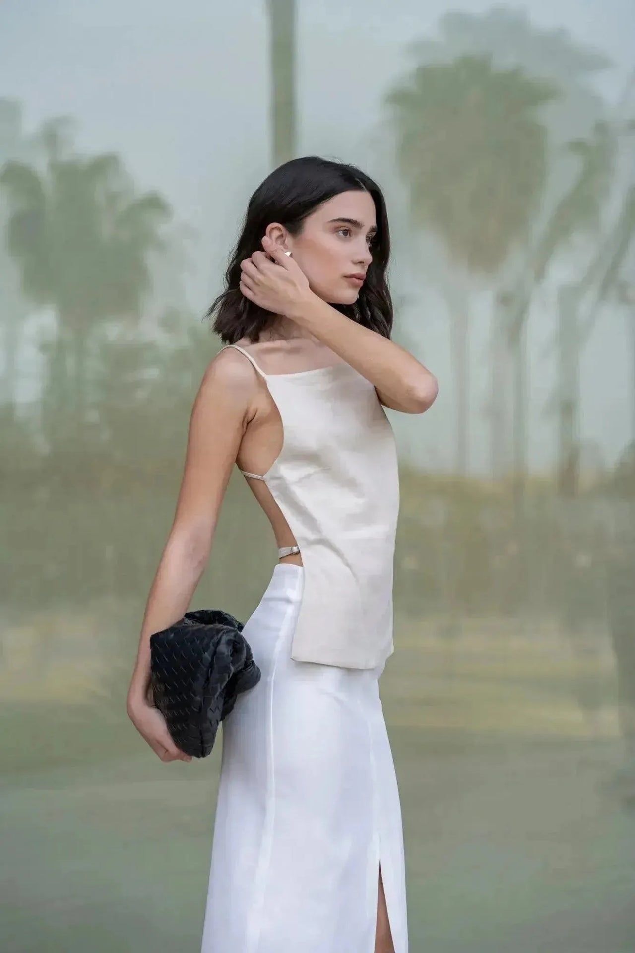 Modèle en jupe blanche longue femme de profil, montrant la coupe élégante et la fente discrète.