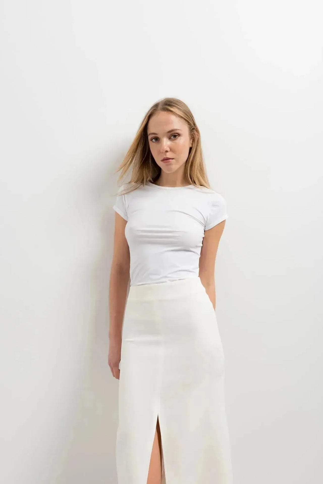 Portrait d'une femme avec une jupe blanche longue femme, soulignant un look minimaliste et élégant.