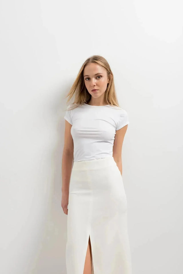 Portrait d'une femme avec une jupe blanche longue femme, soulignant un look minimaliste et élégant.