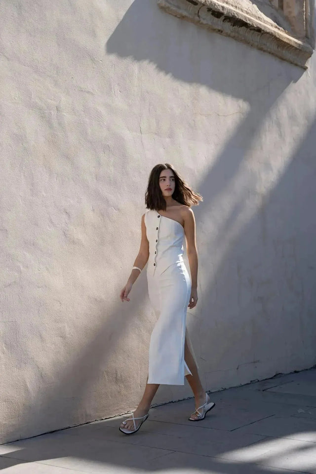 Modèle marchant avec assurance dans une jupe blanche longue femme fendue arrière, offrant un look chic et moderne.