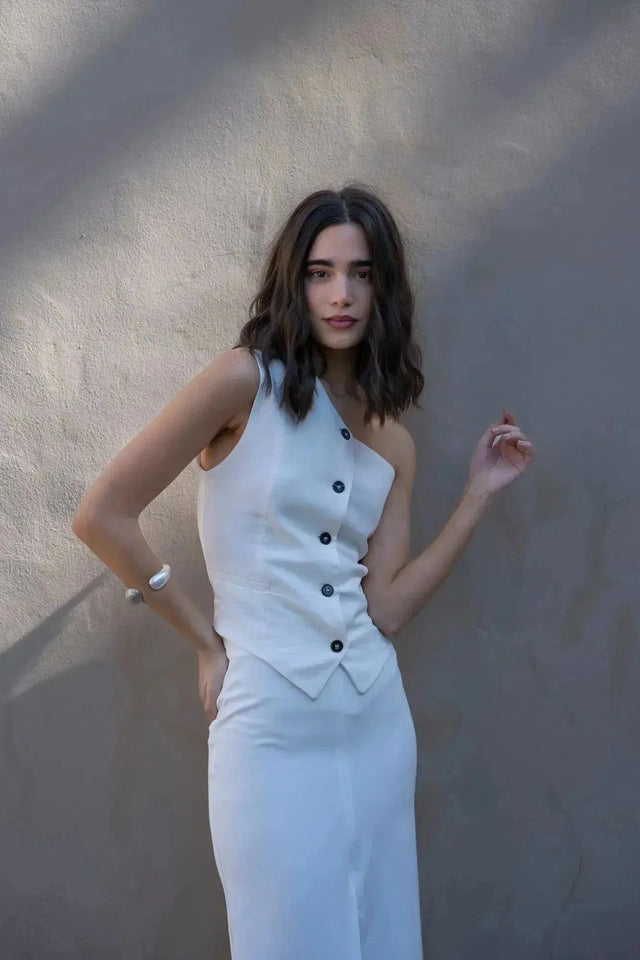 Gros plan sur une femme avec une jupe blanche longue femme, soulignant le style asymétrique et les boutons décoratifs.