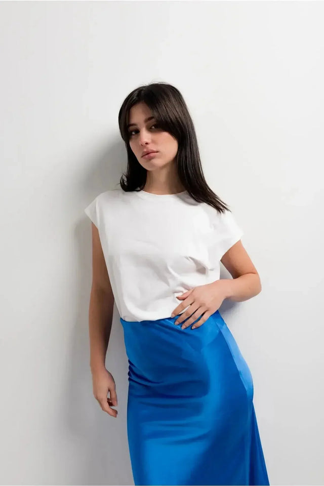 Gros plan sur une femme mettant en avant la Jupe Satin Bleue Électrique Midi, alliant confort et élégance avec un haut blanc.
