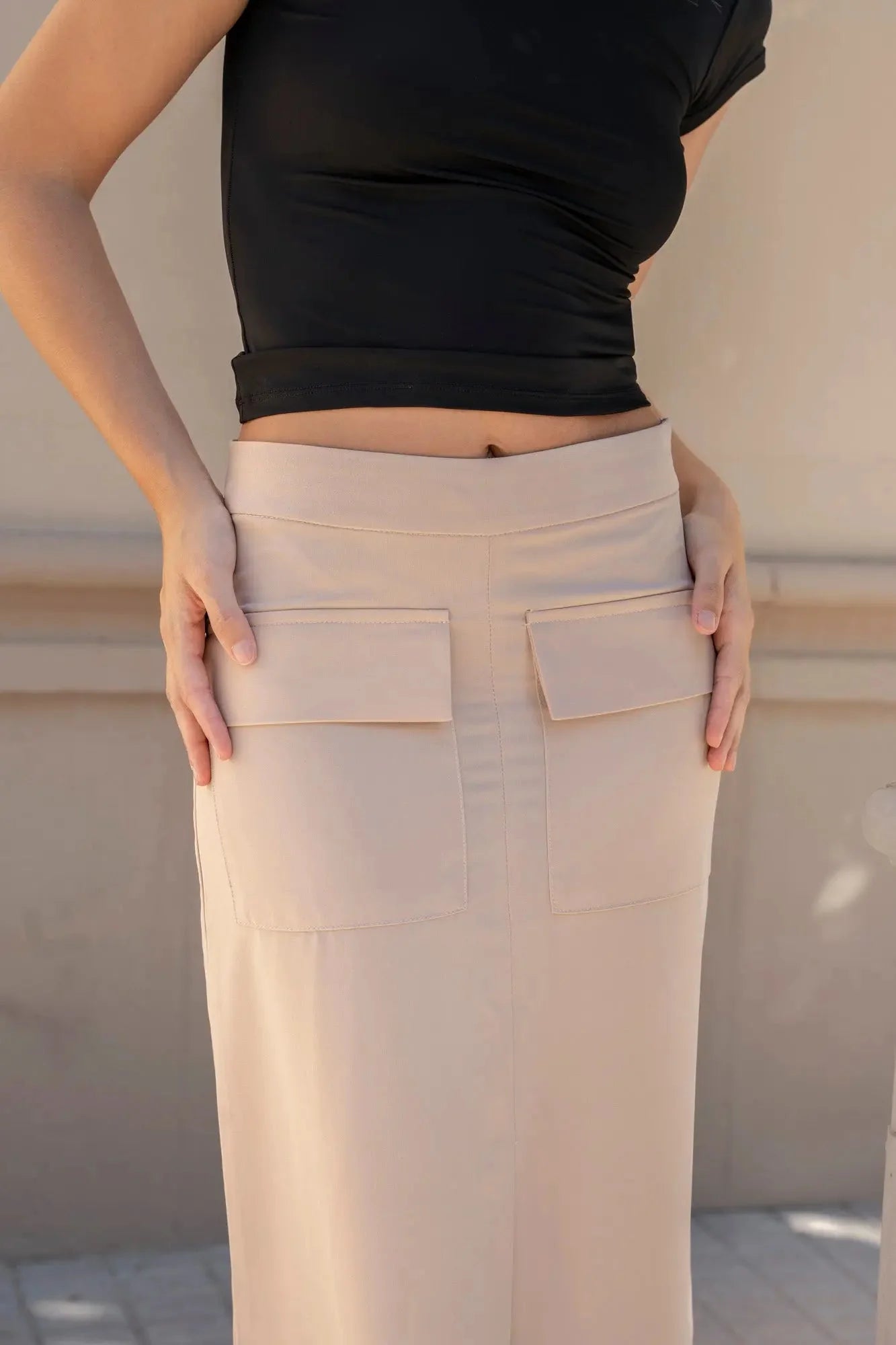 Zoom sur la jupe cargo femme beige avec des poches pratiques, portée avec un haut noir.