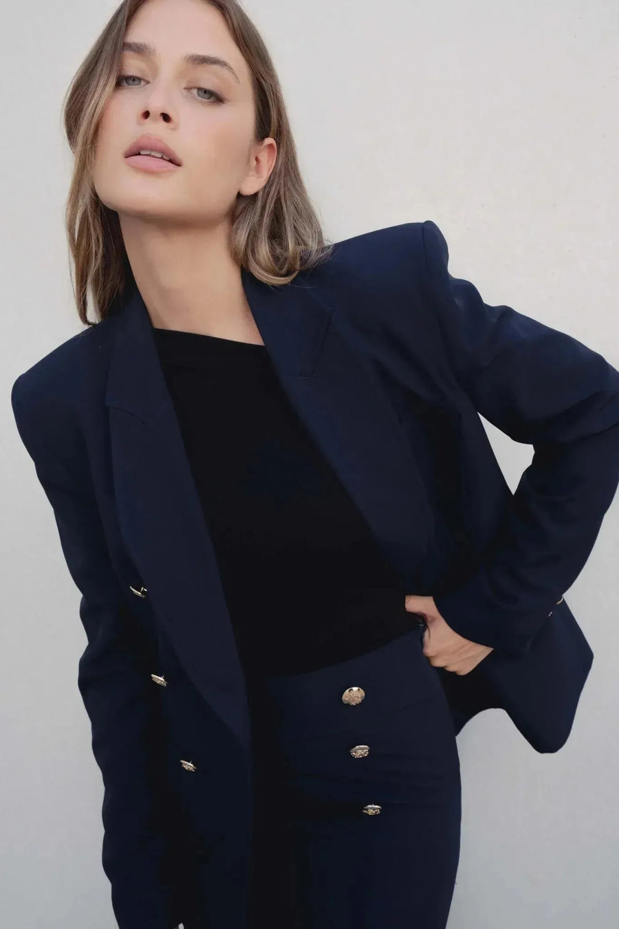 Femme à boutons dorés portant un blazer marine et une jupe femme assortie