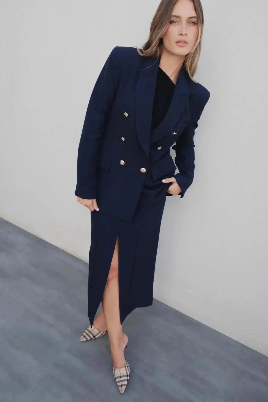 Femme à boutons dorés portant un blazer marine et une jupe femme assortie