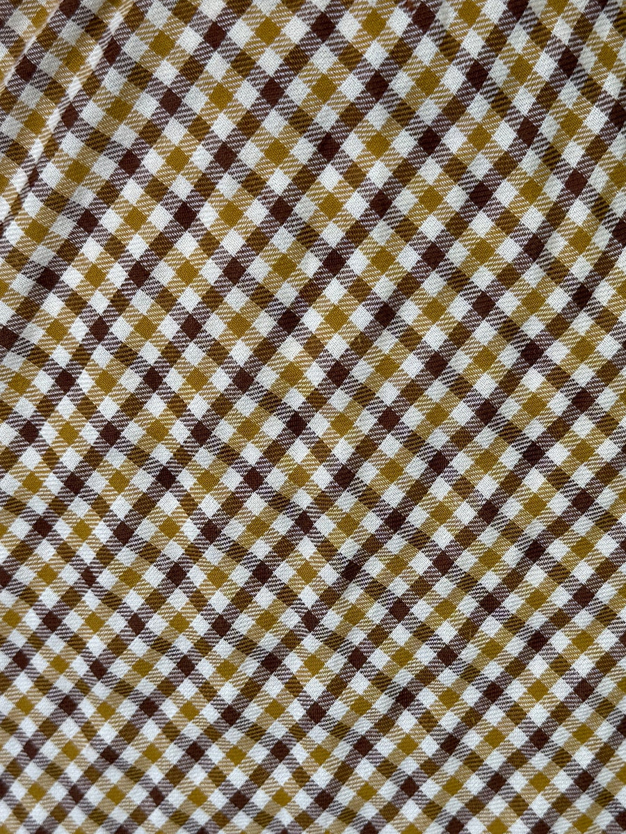 Gros plan sur les carreaux jaune moutarde, marron et blancs de la jupe.