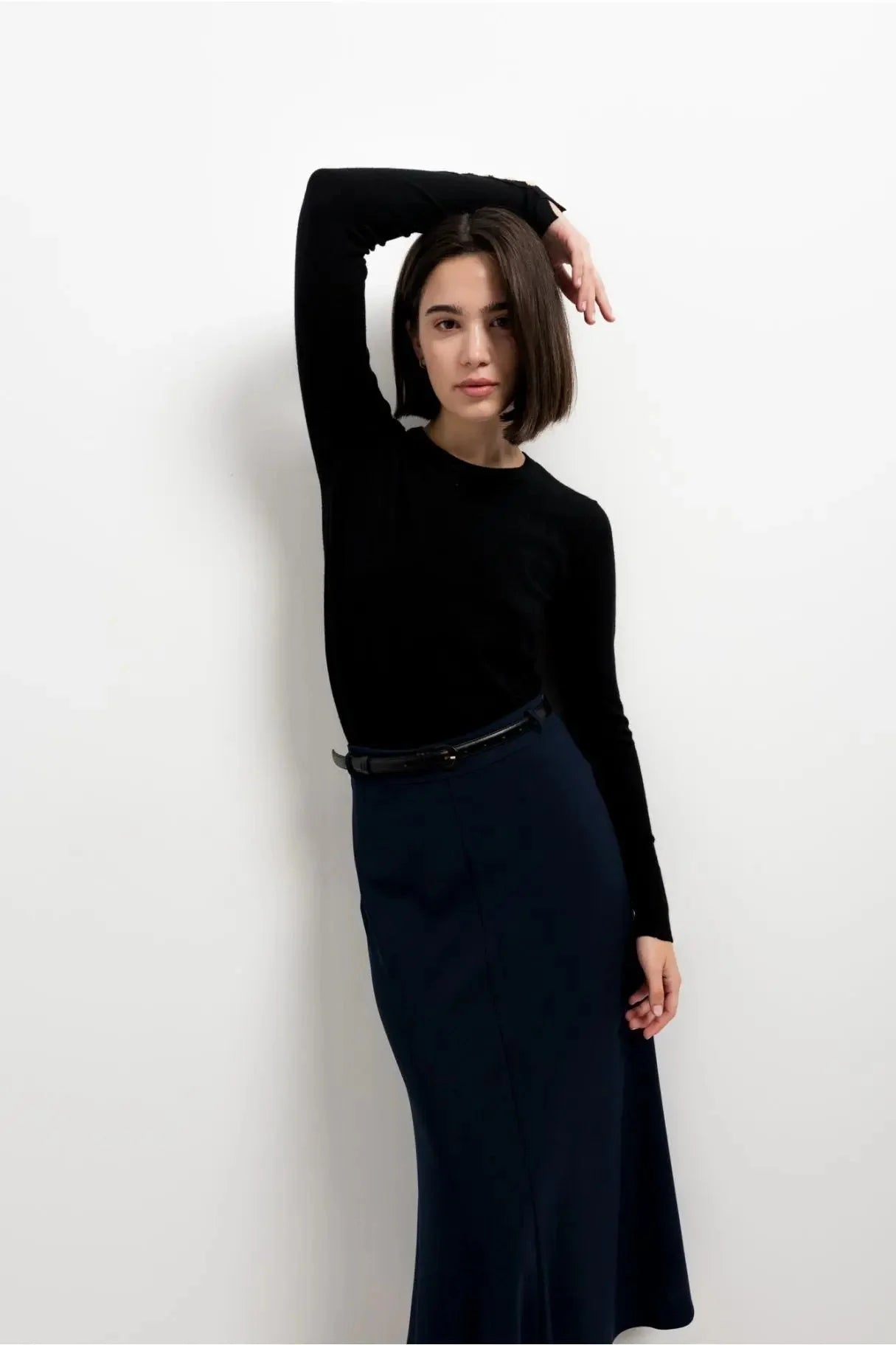 Femme portant une jupe midi avec ceinture et un haut noir longue manche