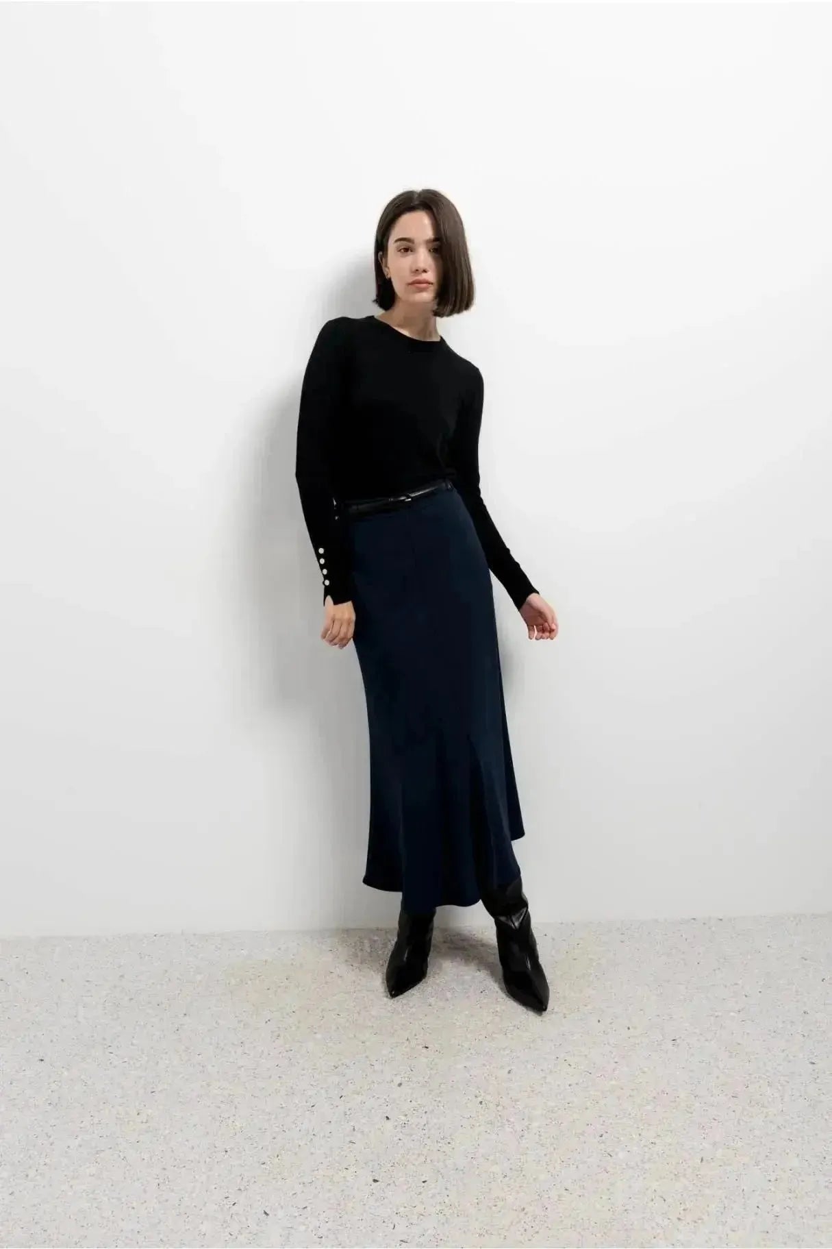 Femme posant avec élégance dans une jupe avec ceinture, coloris navy, accessoirisée avec une ceinture pour une silhouette flatteuse.
