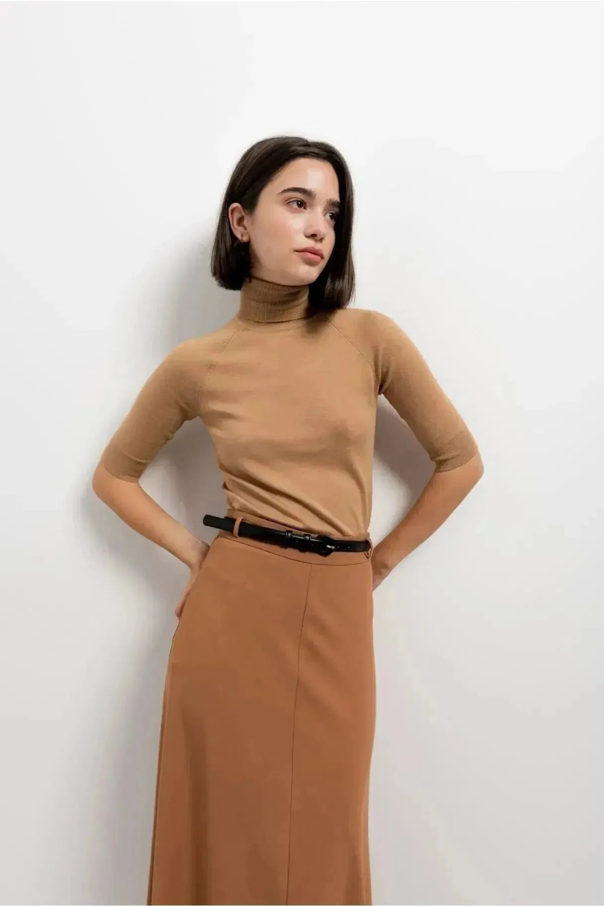 Close-up d'un modèle en jupe avec ceinture couleur camel, soulignant l'élégance de la jupe midi et son confort.