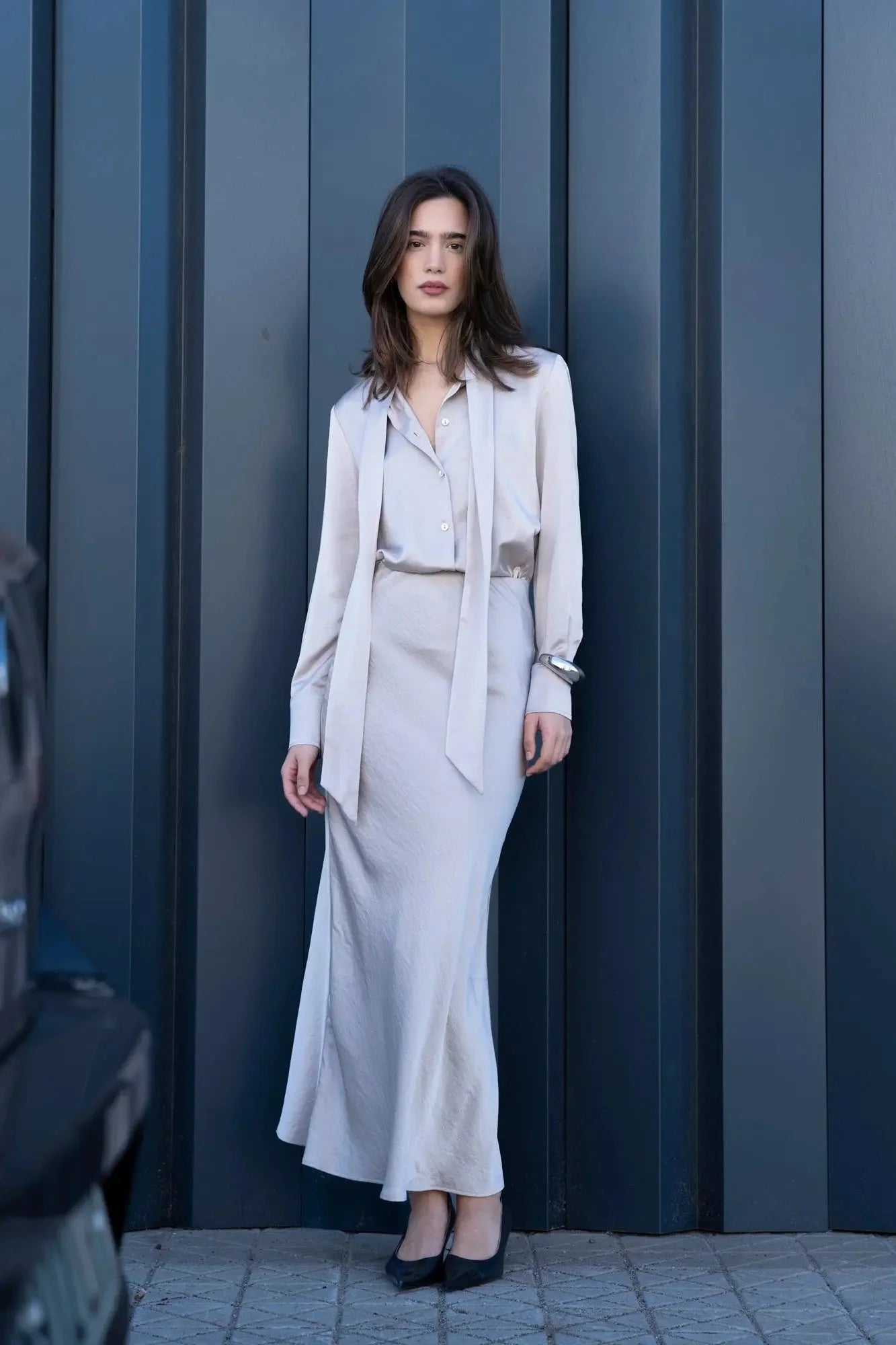 Femme portant une jupe midi en satin gris et un ensemble assorti pour un look élégant