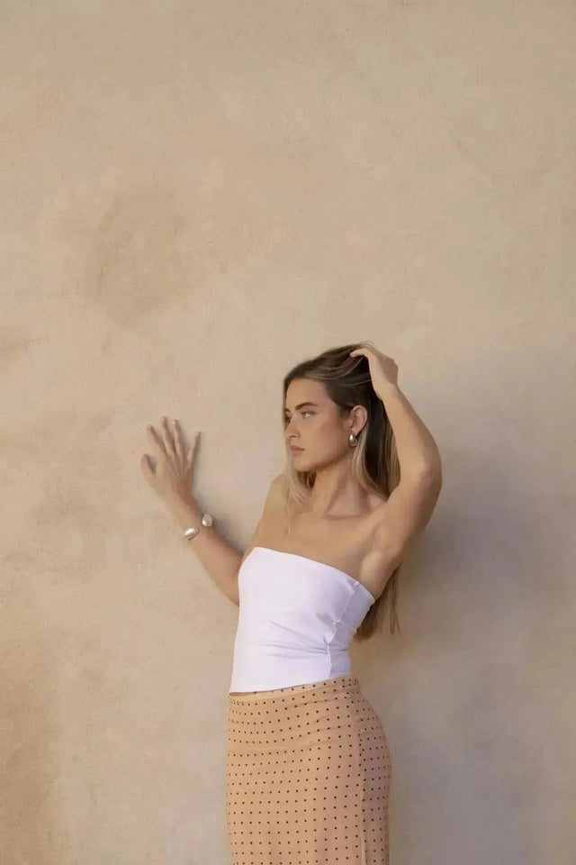 Femme portant une jupe midi imprimée à pois pêche et haut blanc strapless